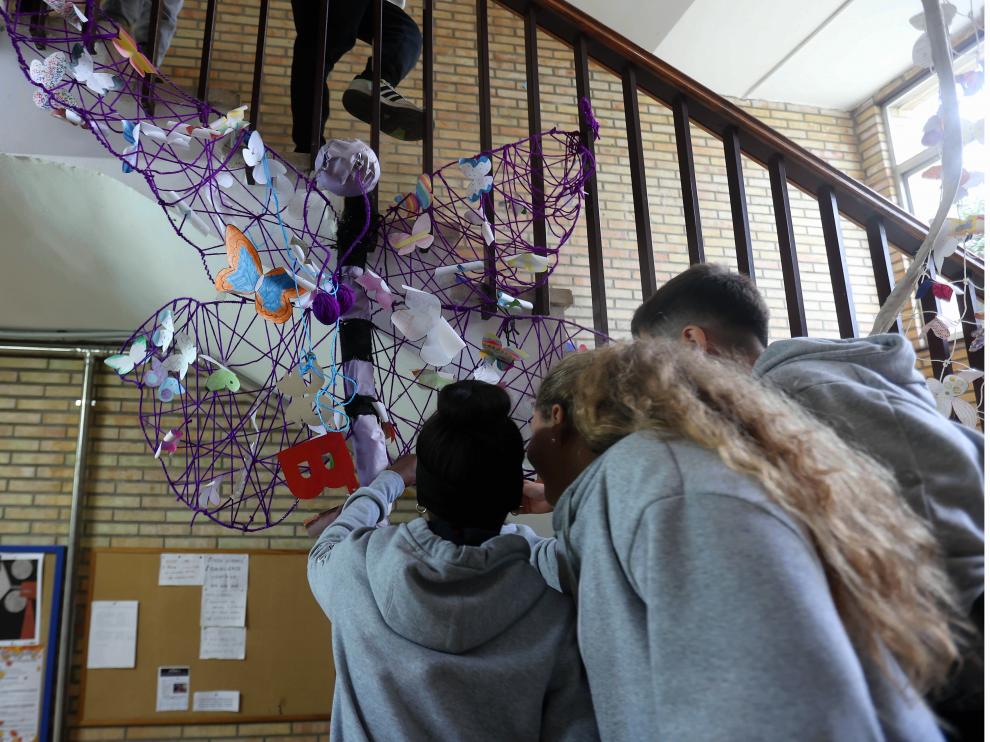 Alumnado del IES Lucas Mallada, junto a la estructura de mariposas creada con motivo del 25N.