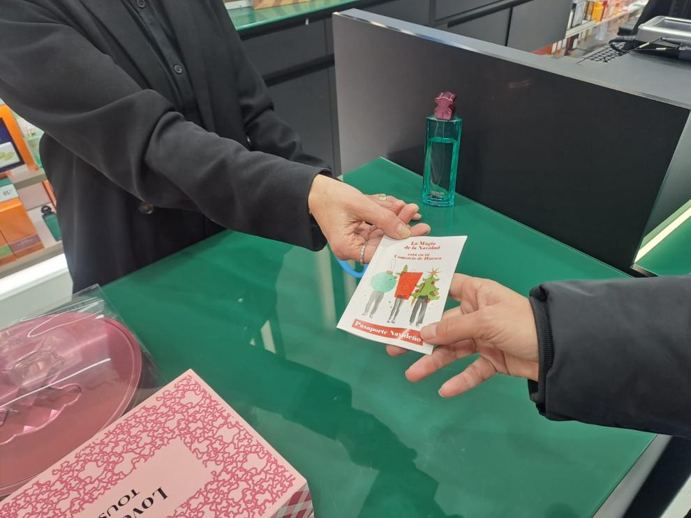 Entrega a una clienta de un ‘pasaporte’ de la campaña navideña de Comercio de Huesca.