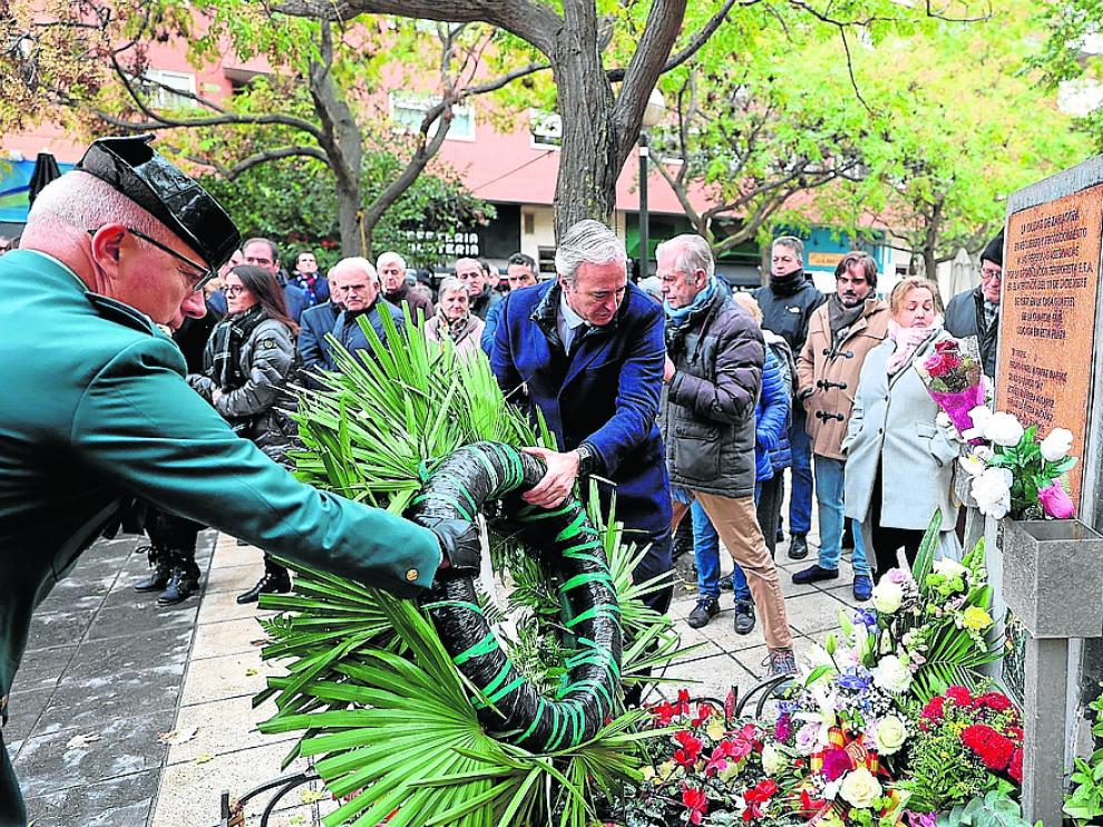 Jorge Azcón y un agente de la Guardia Civil entregan una corona de flores en el lugar del homenaje.
