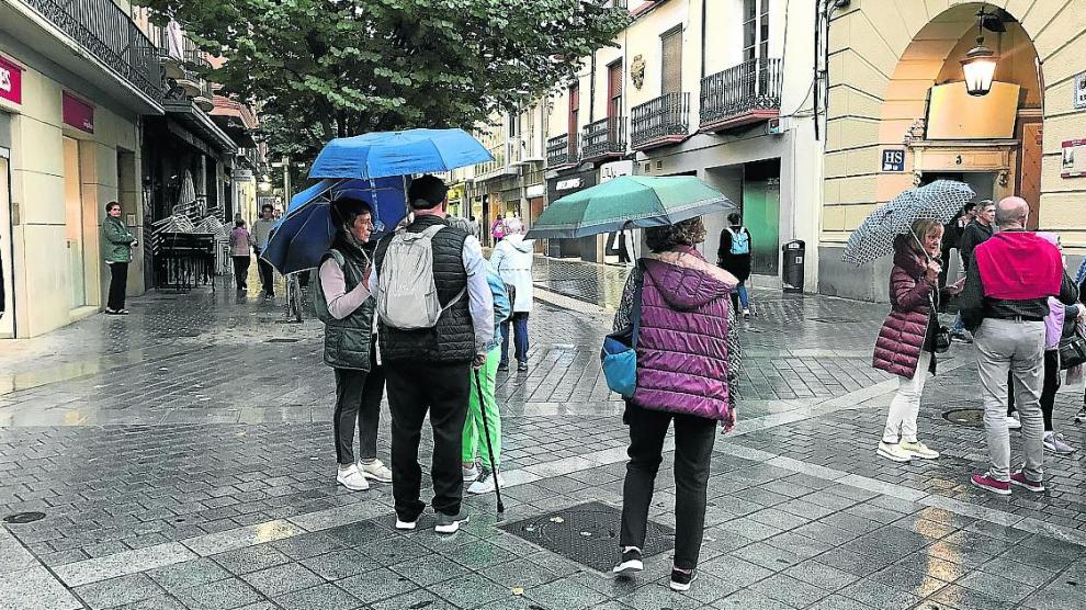 Ciudadanos ayer con sus paraguas en el Coso.
