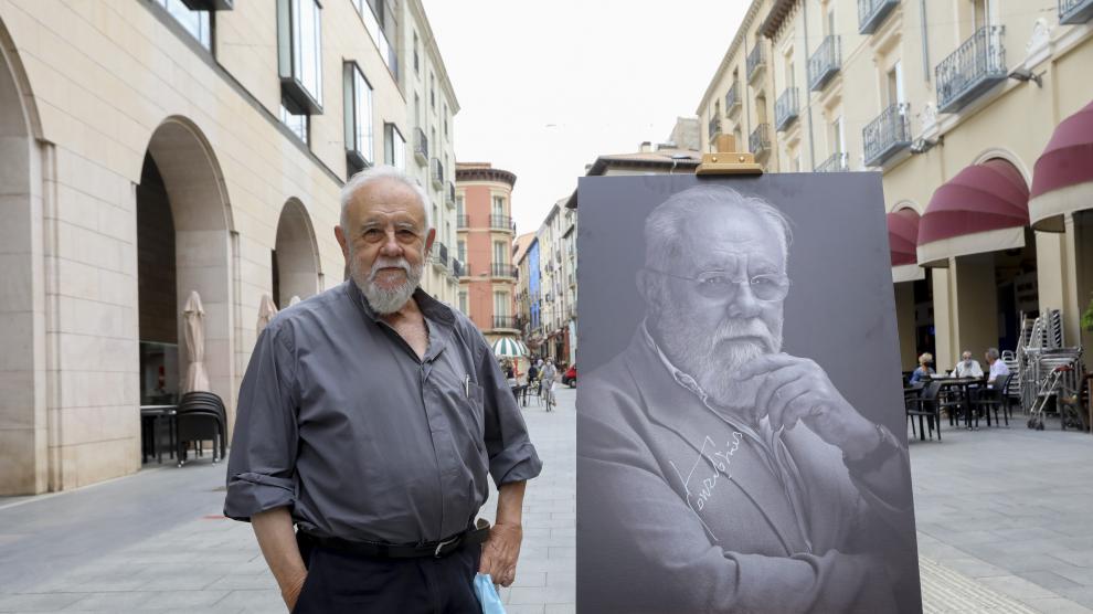 Gonzalo Suárez, posando con su retrato en los Porches de Galicia.