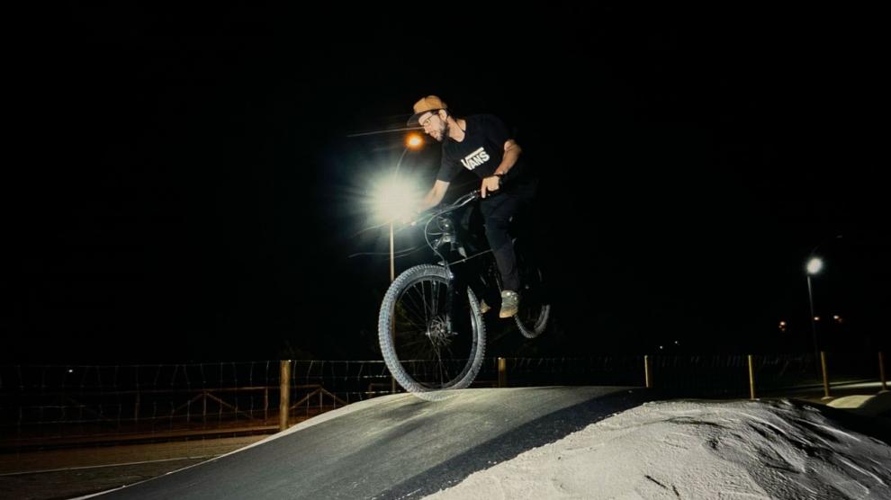 Biker realiza trucos en las instalaciones del Pump Truck de Villanúa iluminado durante la noche.