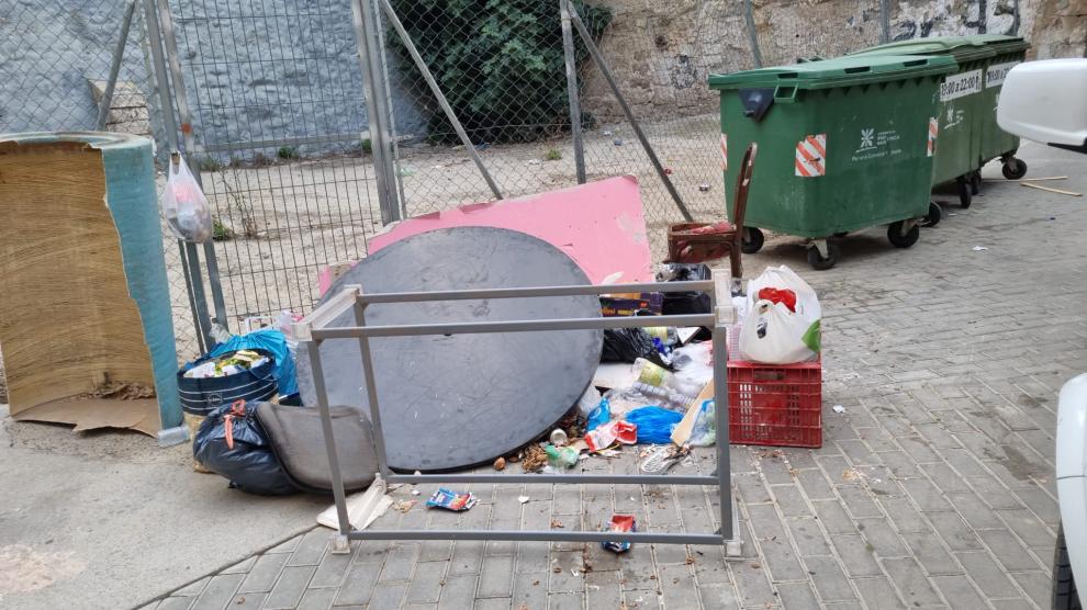 Distintos escombros depositados en una calle de Fraga junto a unos contenedores.