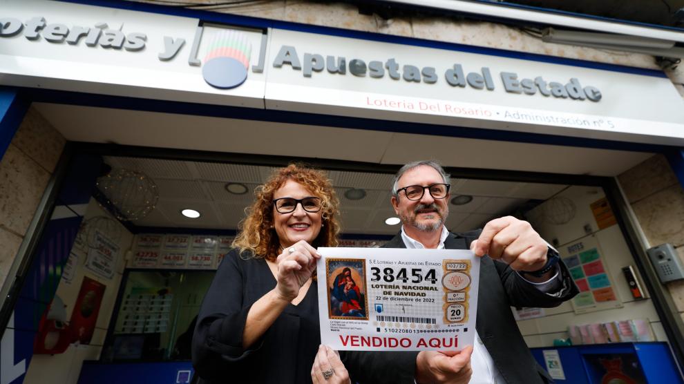 Los propietarios de la administración 'Lotería del Rosario' posan con una réplica del número 38454, uno de los quintos premios.