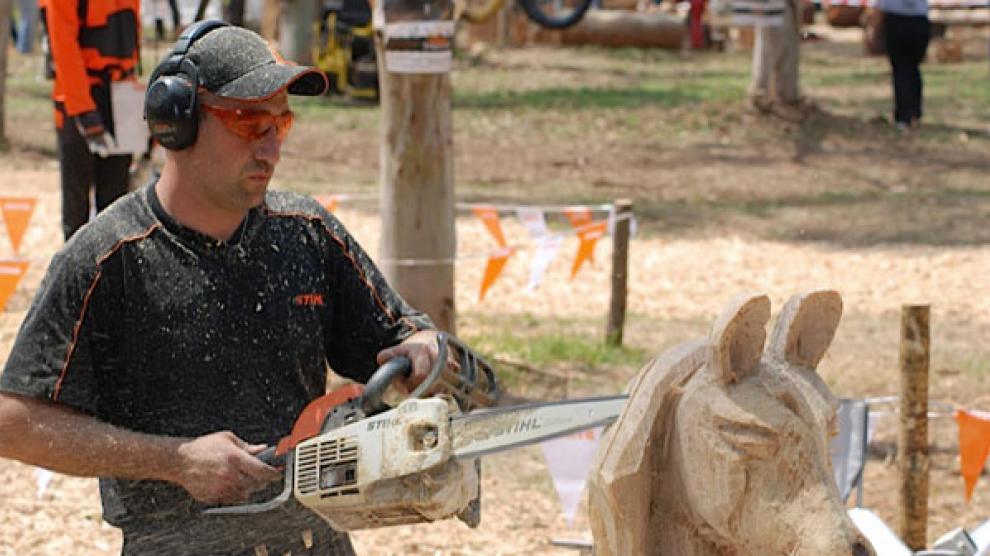 Abel Vicente talla madera con una motosierra para dar crear una figura de un caballo.