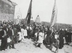 El pueblo de Sariñena, de todas las edades, asiste a la procesión del año 1934, con banderas y santos identificados en la imagen. FOTO