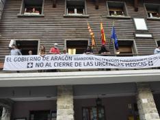 Vecinos de la zona colocando la pancarta contra el cierre de las urgencias médicas en el balcón del Ayuntamiento de Canfranc. pac