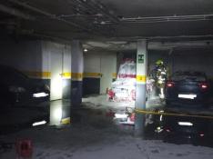 Intervención de los bomberos en el garaje de Monzón, con el vehículo calcinado.